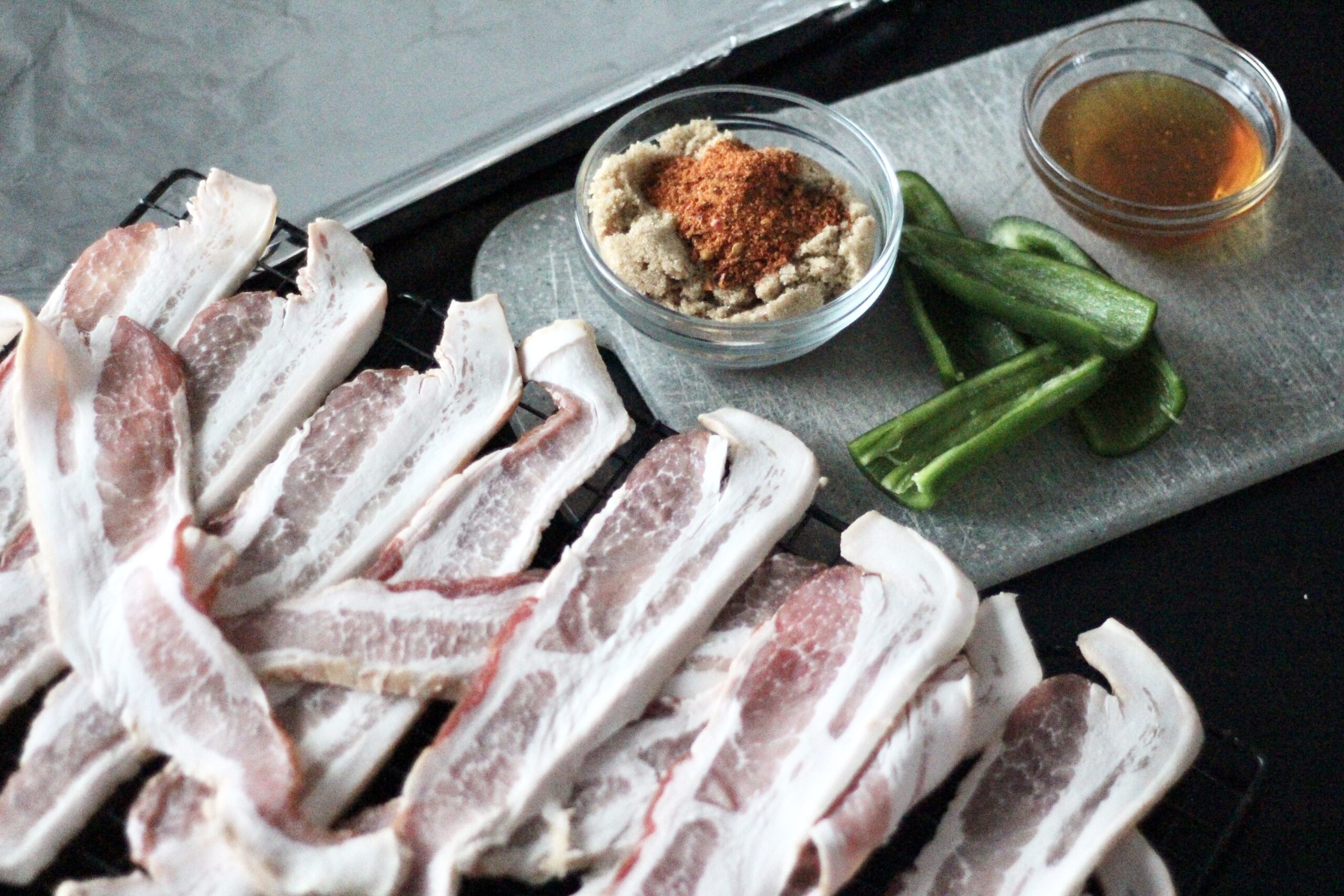 Raw bacon strips on a table with other ingredients