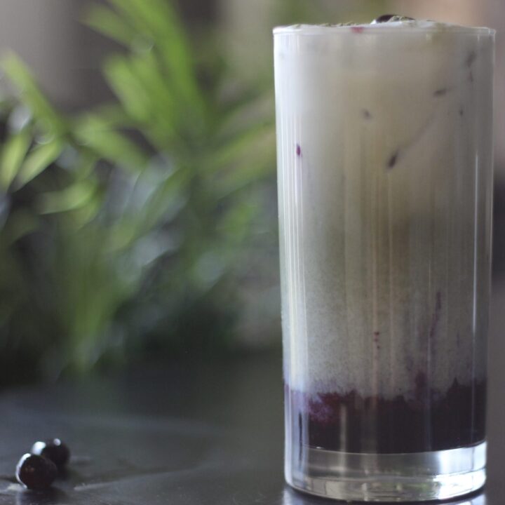 Blueberry Matcha latte sitting on table with blueberries next to it