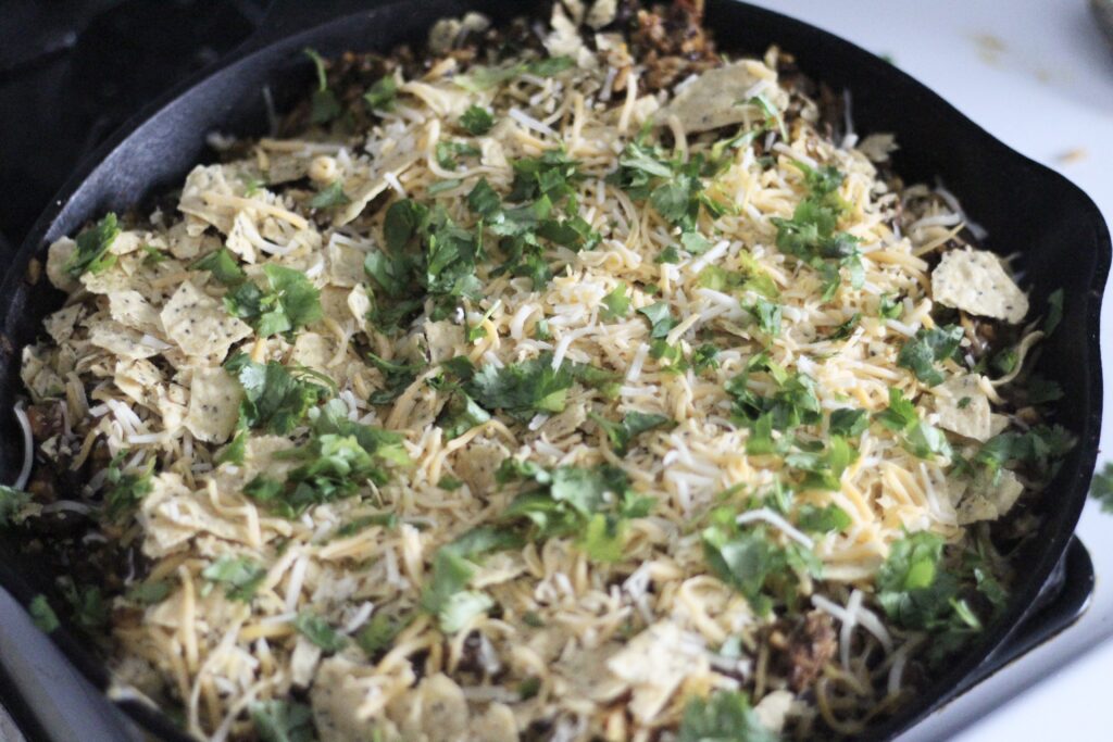 Shredded cheese and cilantro sprinkled on top of taco skillet