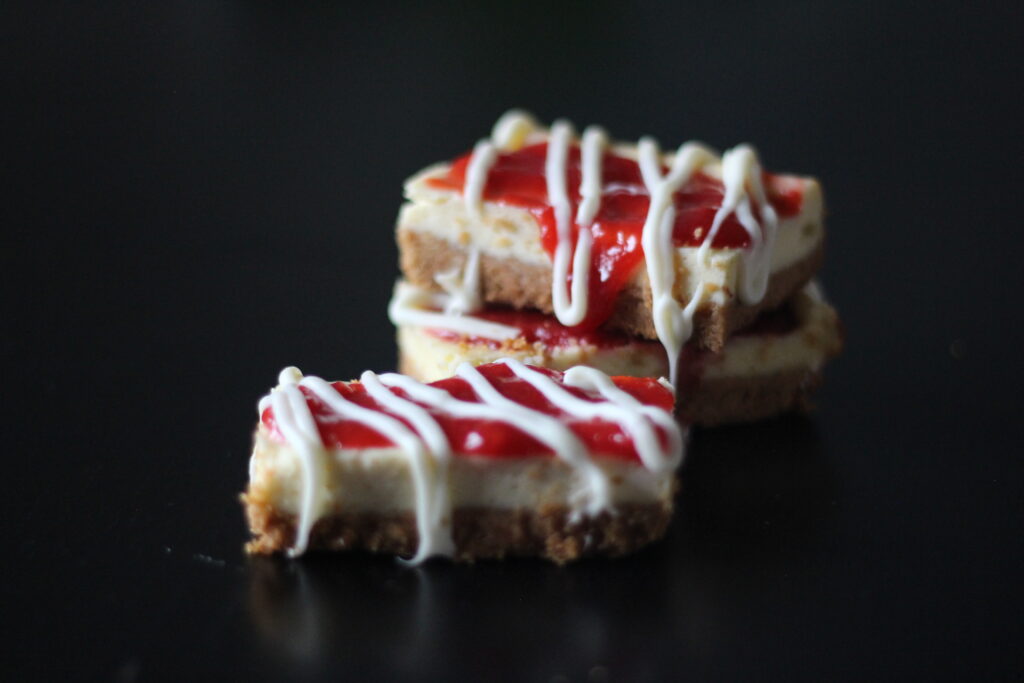 Strawberry cheesecake bars on a black table