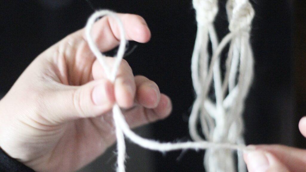 Hand holding macrame cord in a loop