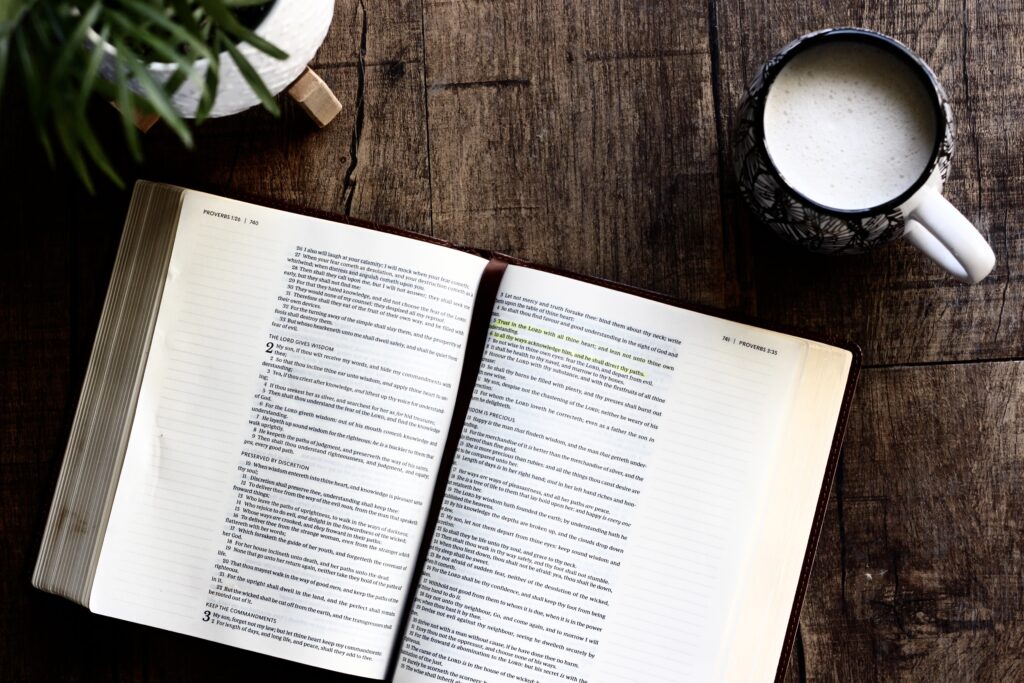 Open bible on a table with a cup of coffee next to it