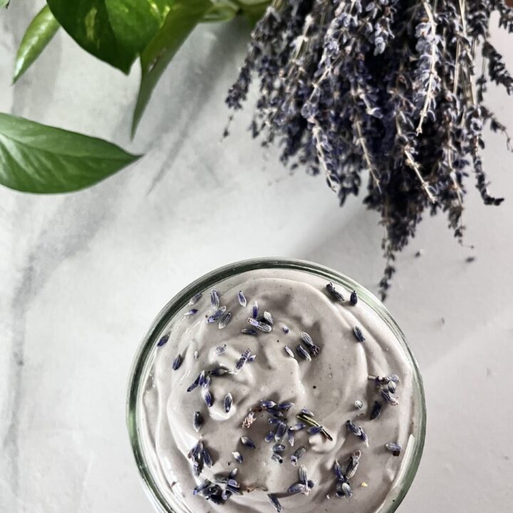 Clay hair mask in glass mason jar on countertop next to lavender plant