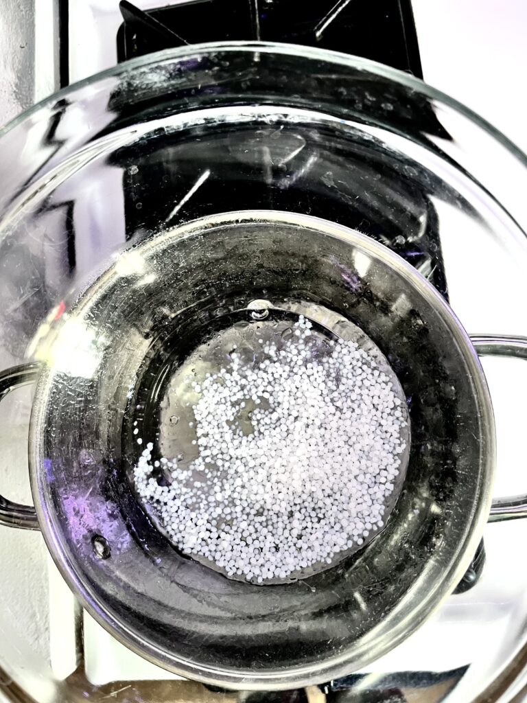 Saucepan over a double boiler melting beeswax pellets